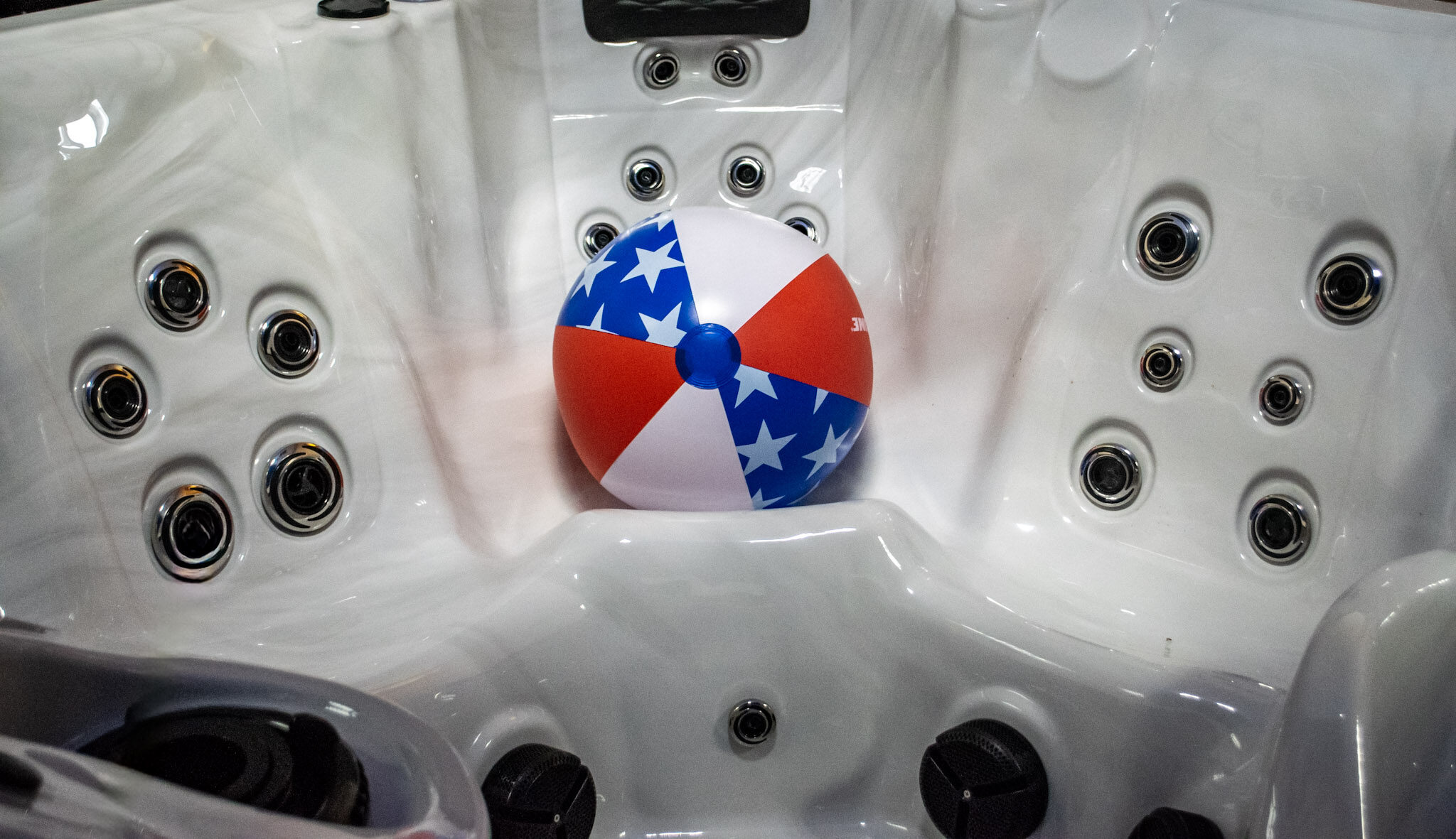 white hot tub interior with red, white, and blue beach ball sitting on a seat